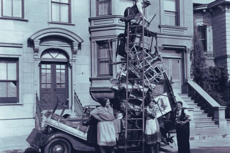 Old photo of four people piling furniture high on top of car